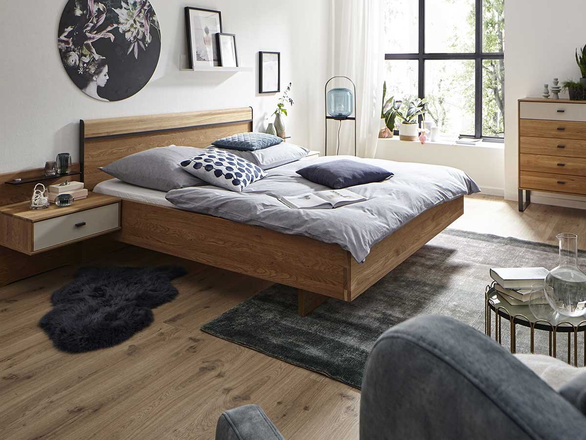 Schlafzimmer mit Holzbett, Kommode und grauem Teppich