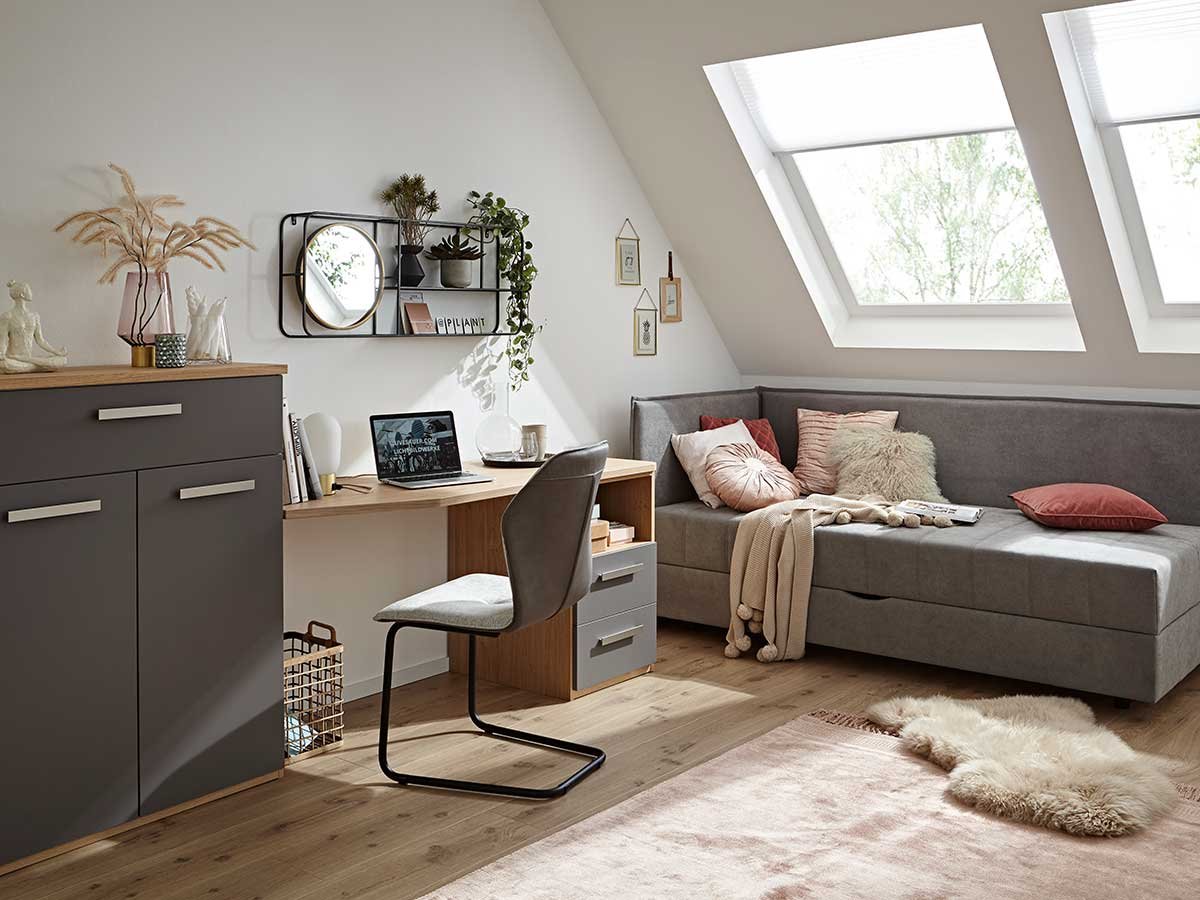 Raum mit kleinem Schreibtisch, Kommode, Polsterbett und Wand Deko