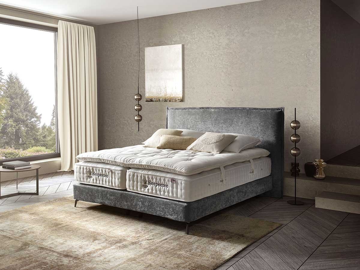 Schlafzimmer mit Polsterbett, hellbraunem Teppich und beigen Vorhängen